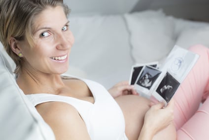 Portrait schwangere Frau liegend betrachtet Ultraschallbilder